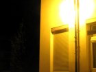 Die blanke Lampe in der Kugelleuchte strahlt viel Licht auf das Haus und in die Fenster statt auf die Stra&szlig;e